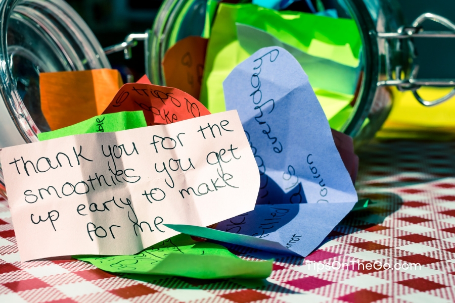 Thank you notes in a jar on a checkered tablecloth. 
