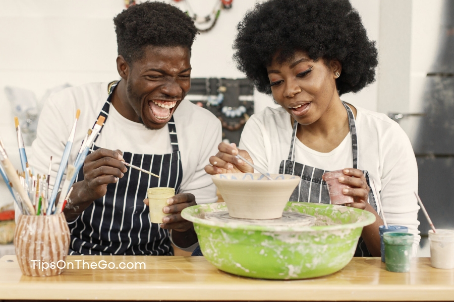 A man and a woman sitting at a table in a pottery studio. 