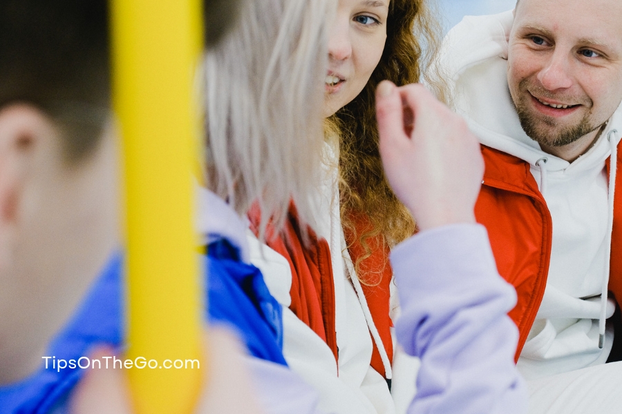 Three people sitting on a bus talking to each other.
